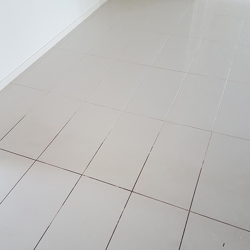 Tiled floor part-way through a grout clean, showing the difference