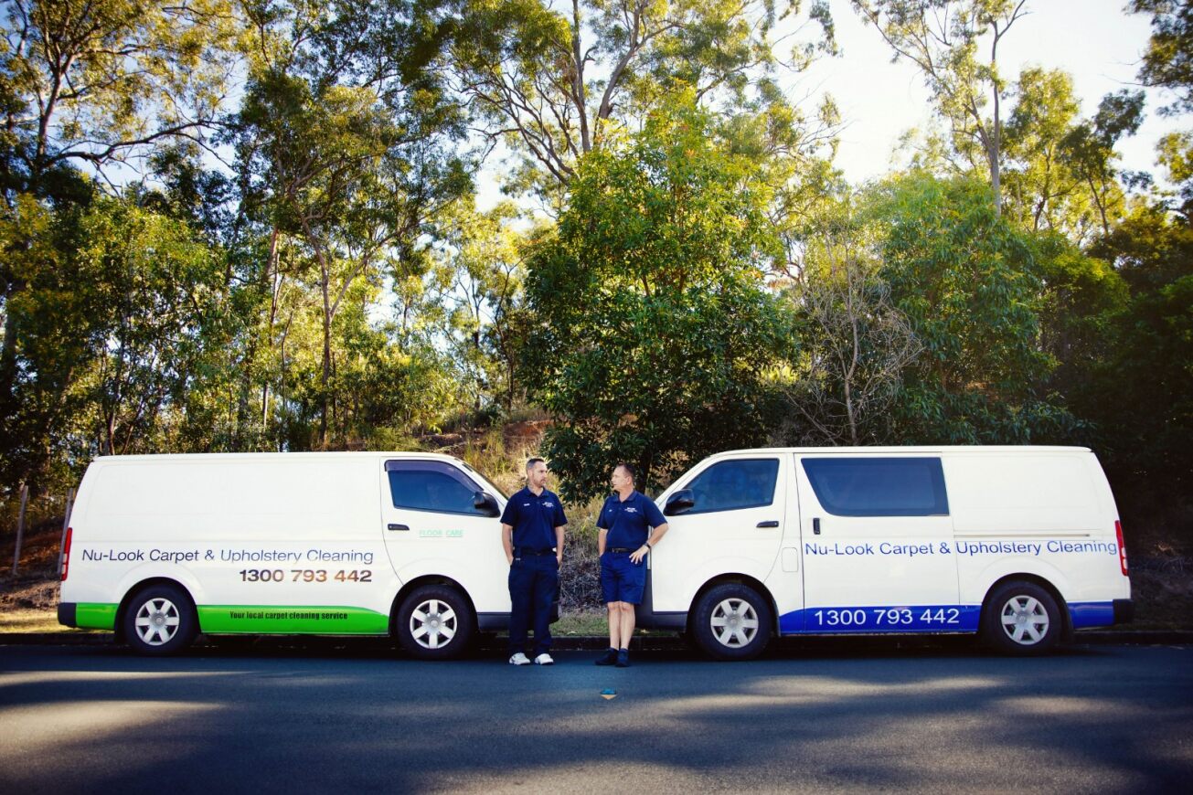 Both branded Nu-Look vans parked side by side with the two technicians standing between them